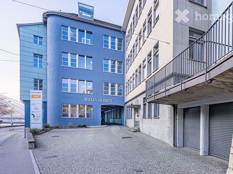 Cobblestone paved road with blue multi-story building, two garages on side