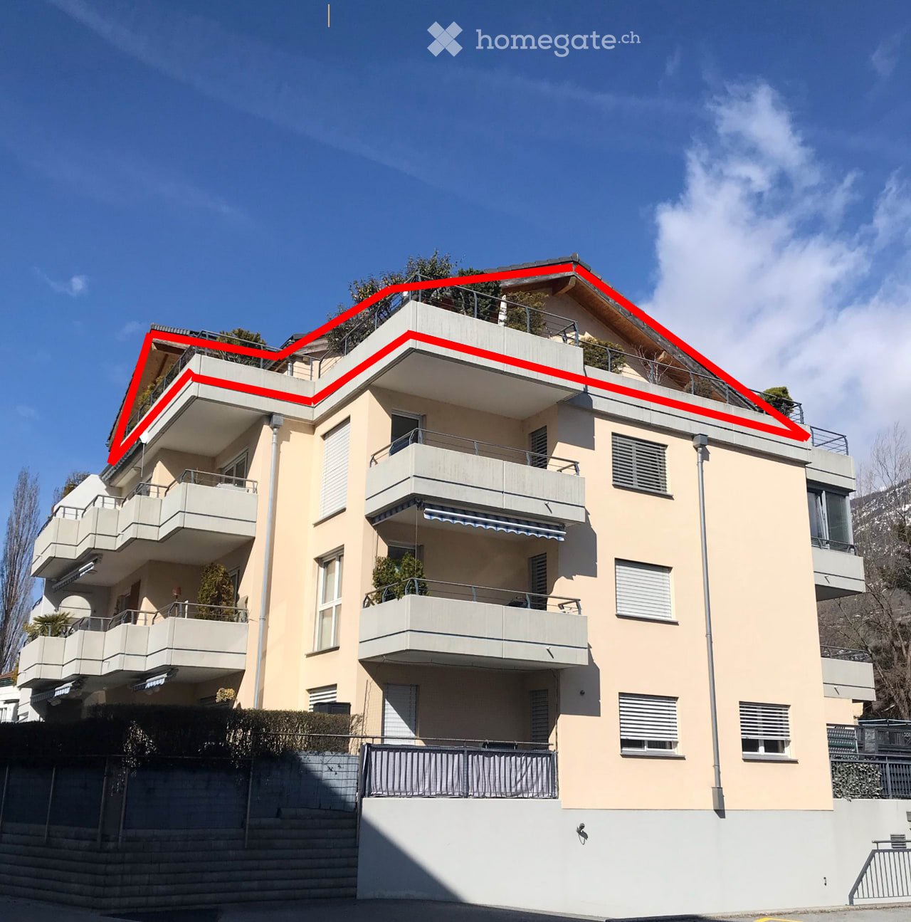 residential building with multiple balconies, red roof line, beige walls