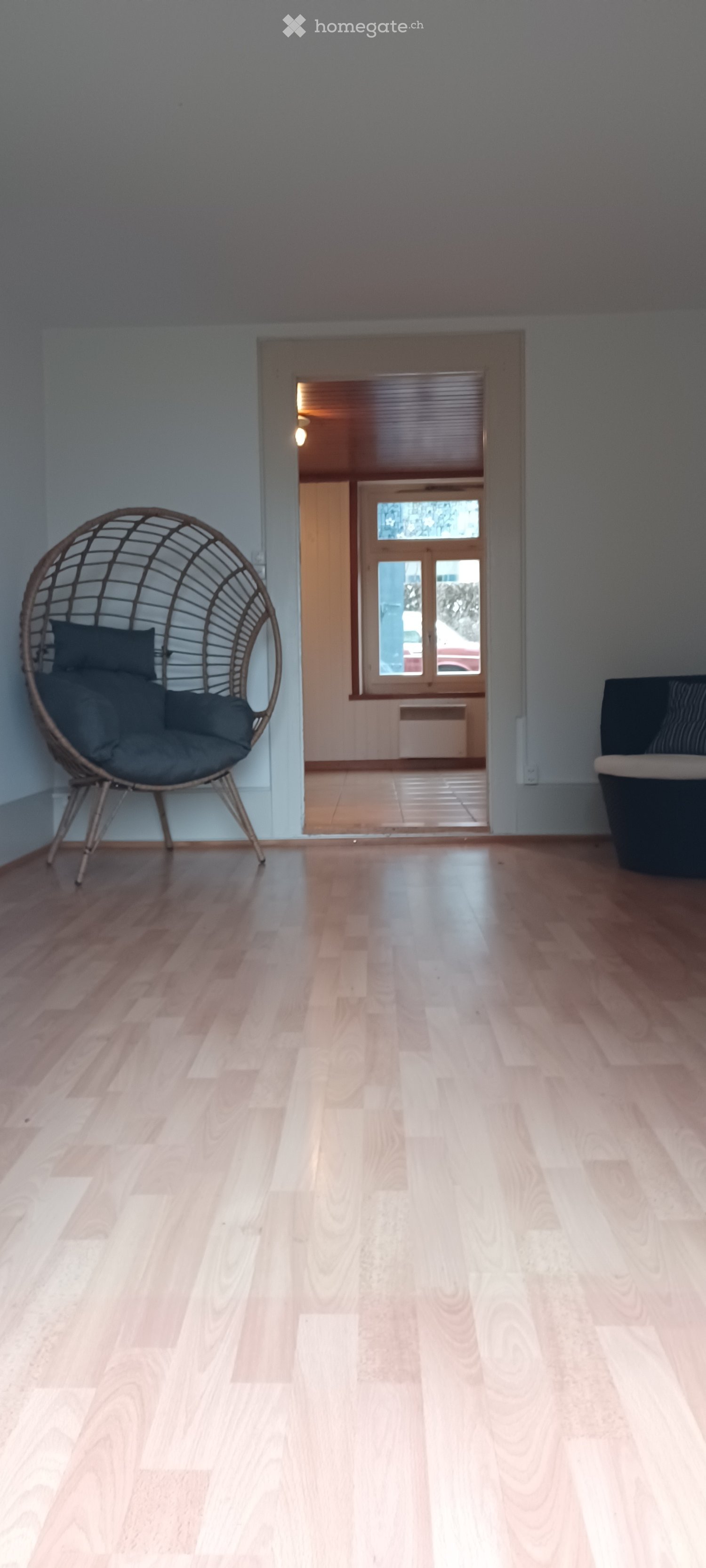 Empty room with wooden floor, two couches, window, wooden cabinet, wooden shelves
