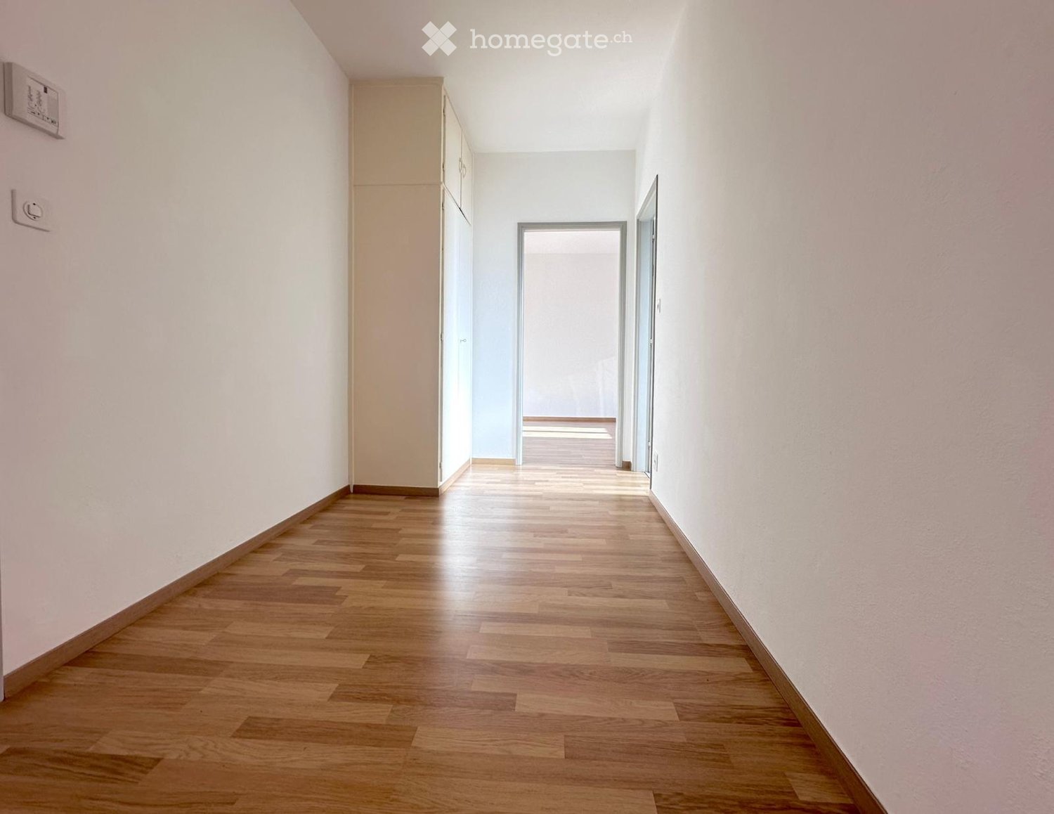 white walls, wooden floor, cabinets on the wall, open doors