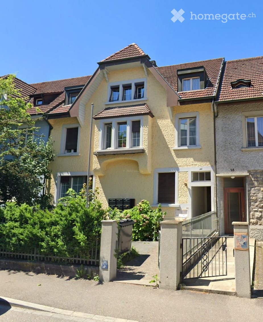 3 story house, beige walls, brown roof, multiple windows, fenced garden