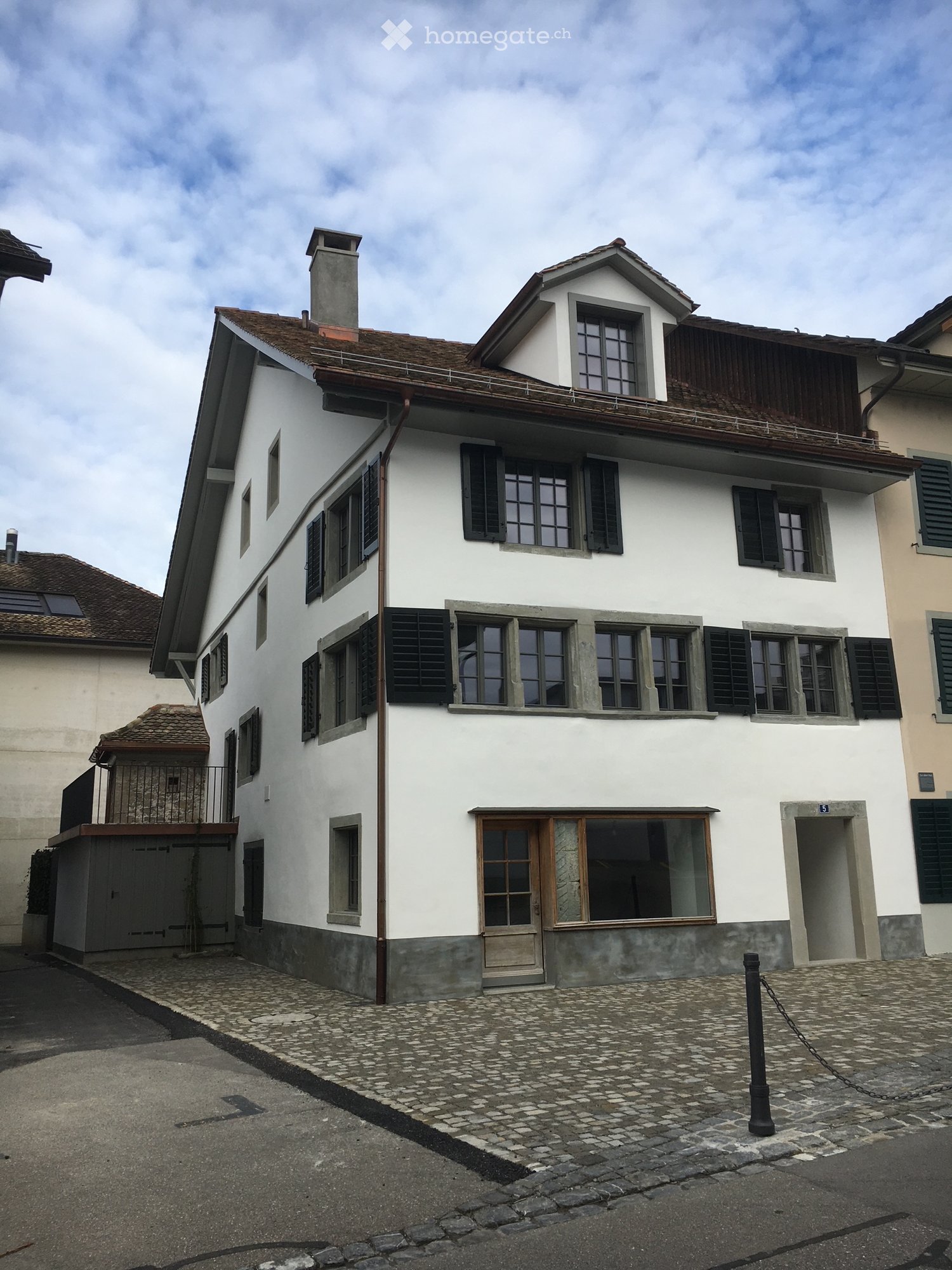 3-story house, white exterior, black shutters, brown roof, multiple windows, small entryway at front