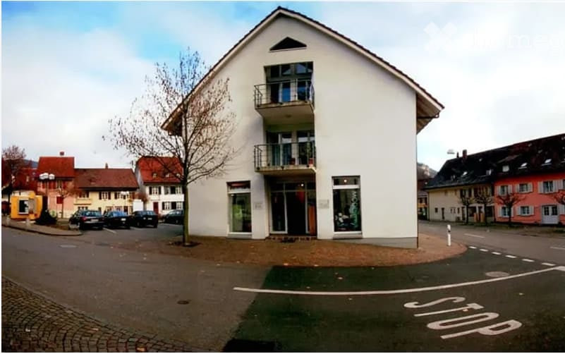 white 3-story house, balcony on the second floor, parking in front of the house