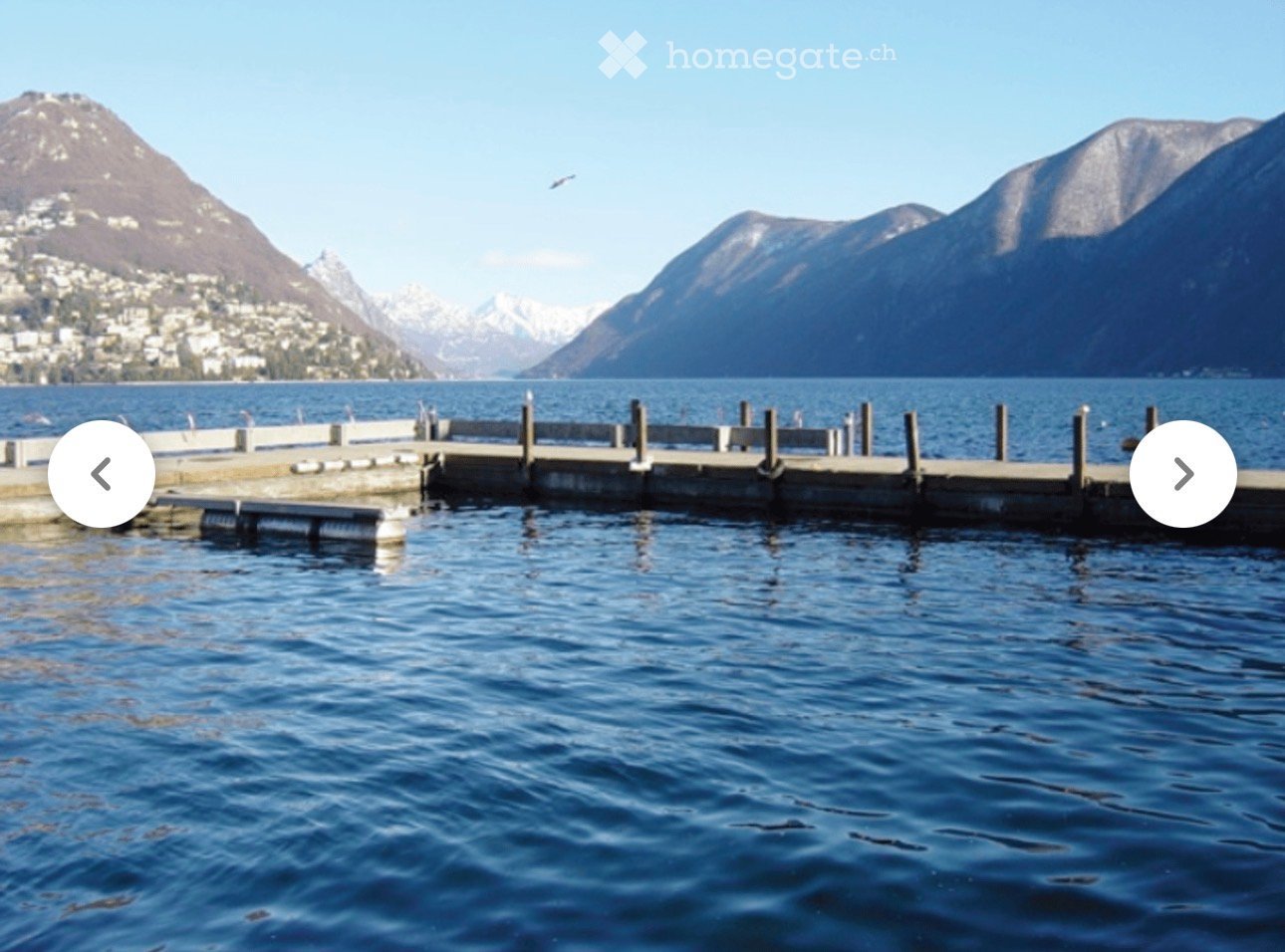 large swimming pool with water, mountains, wooden dock, serene scenery