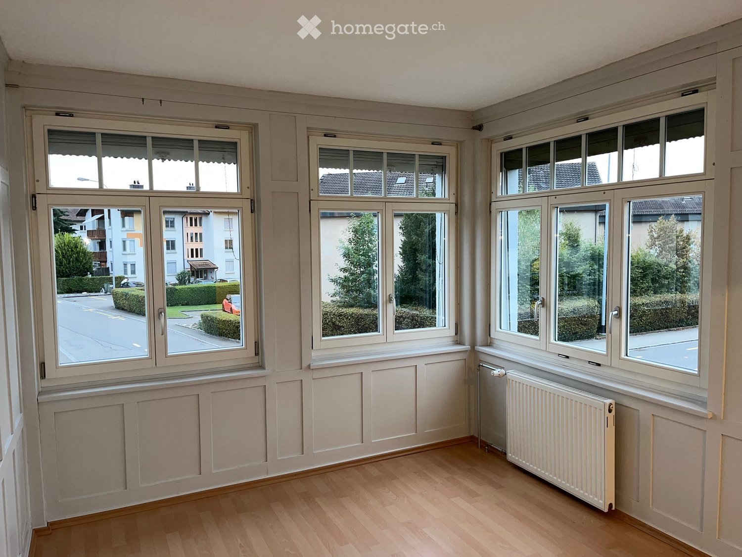 large windows, white walls, white radiator, wooden floor
