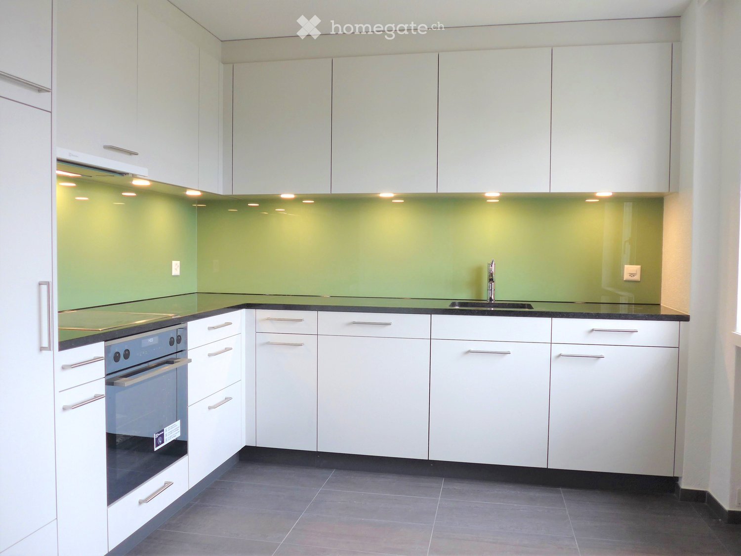white cabinets, green backsplash, black countertops, stainless steel faucet, integrated dishwasher and washing machine