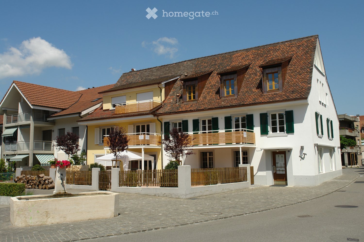2 story building, red roof, green shutters, balconies, yellow front