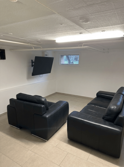 Two black leather sofas with a flat screen TV mounted on the wall
