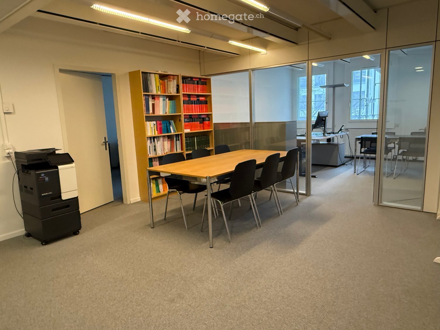 large meeting room with wooden table, chairs, bookcase, and office equipment