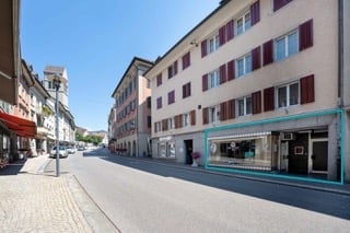 3 story building, beige facade, red shutters, storefront, street