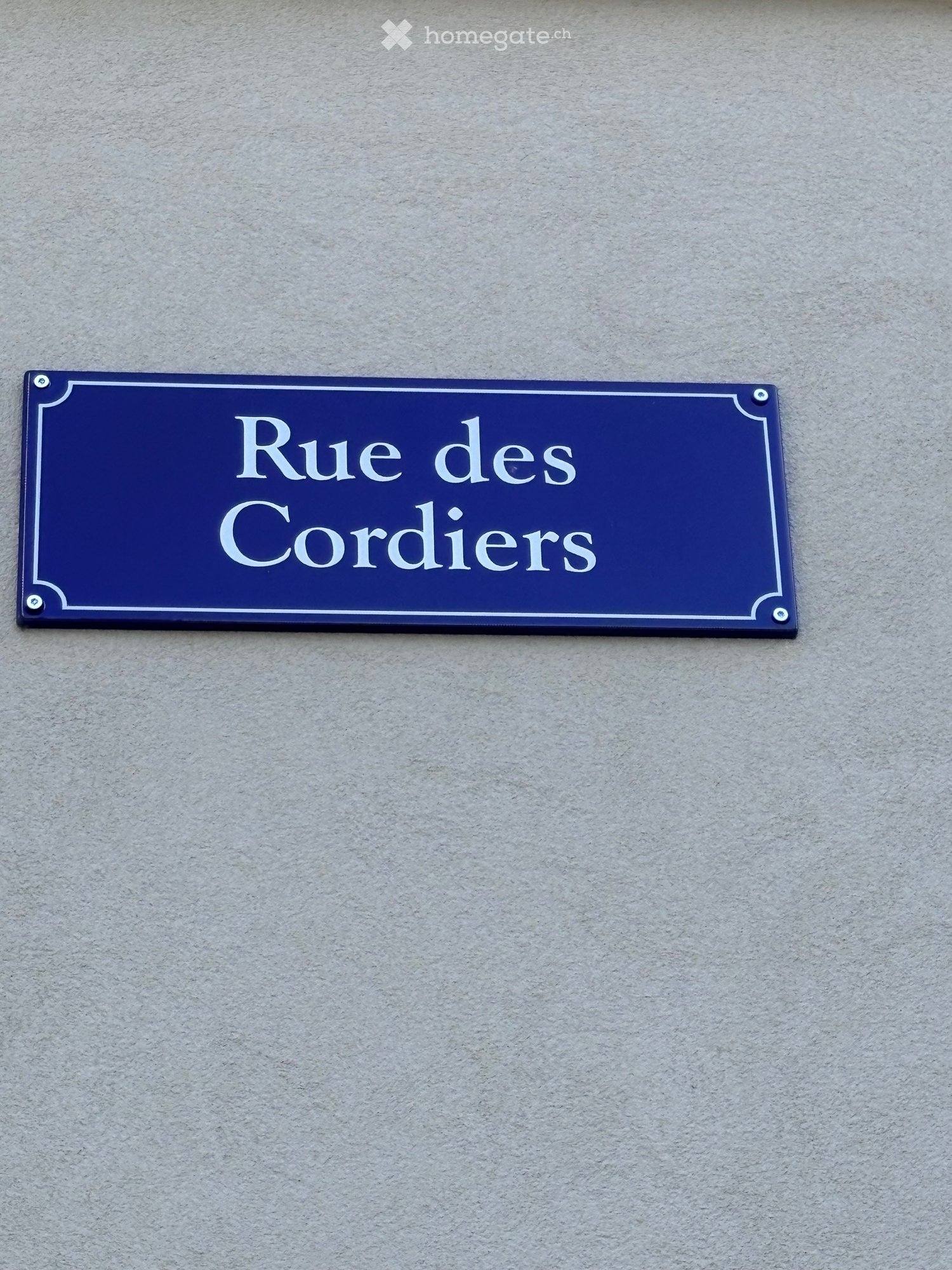 Blue street sign with white text reading 'Rue des Cordiers' mounted on a wall