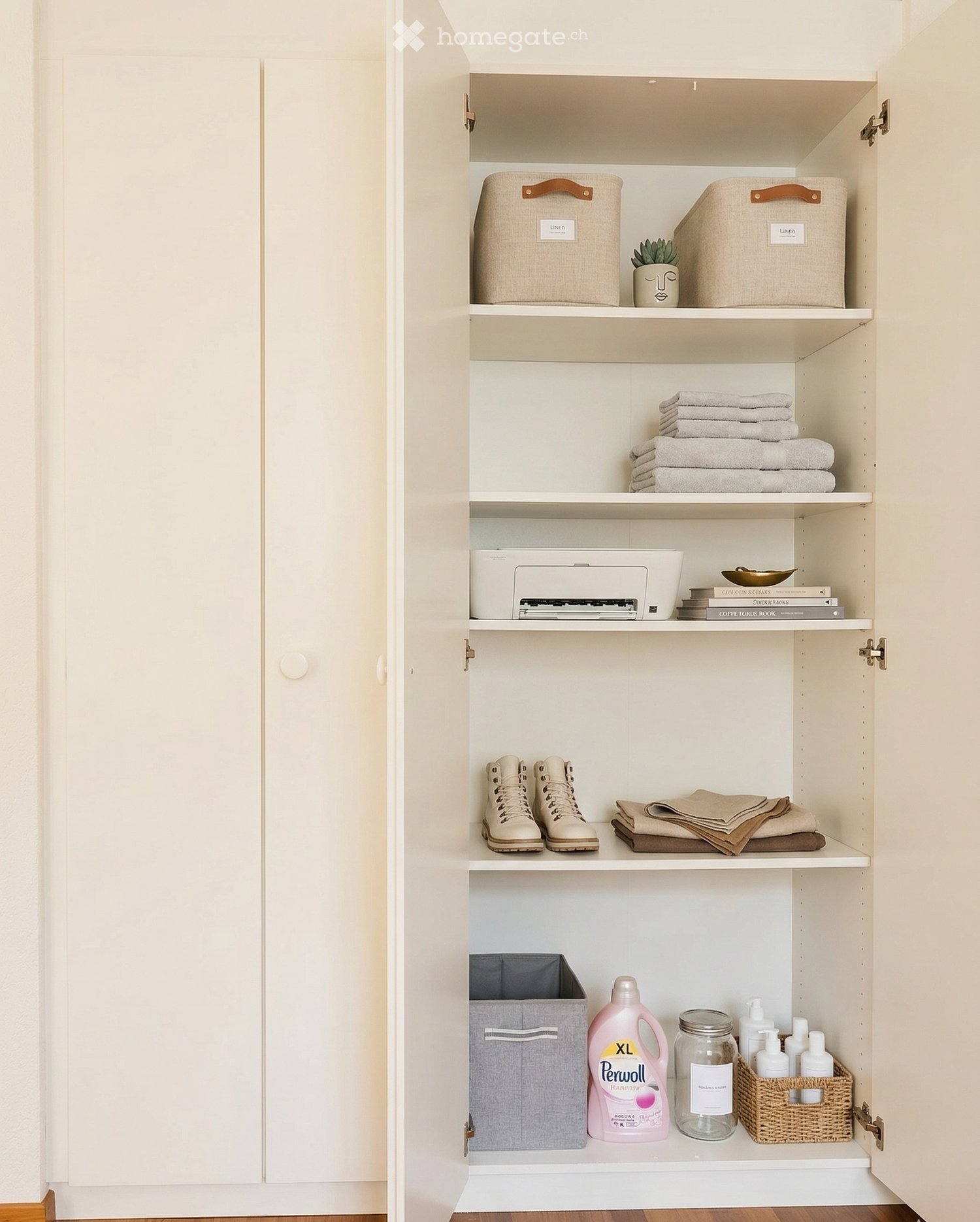 A white wardrobe with multiple shelves, storage boxes, towels, a printer, books, boots, and cleaning products.