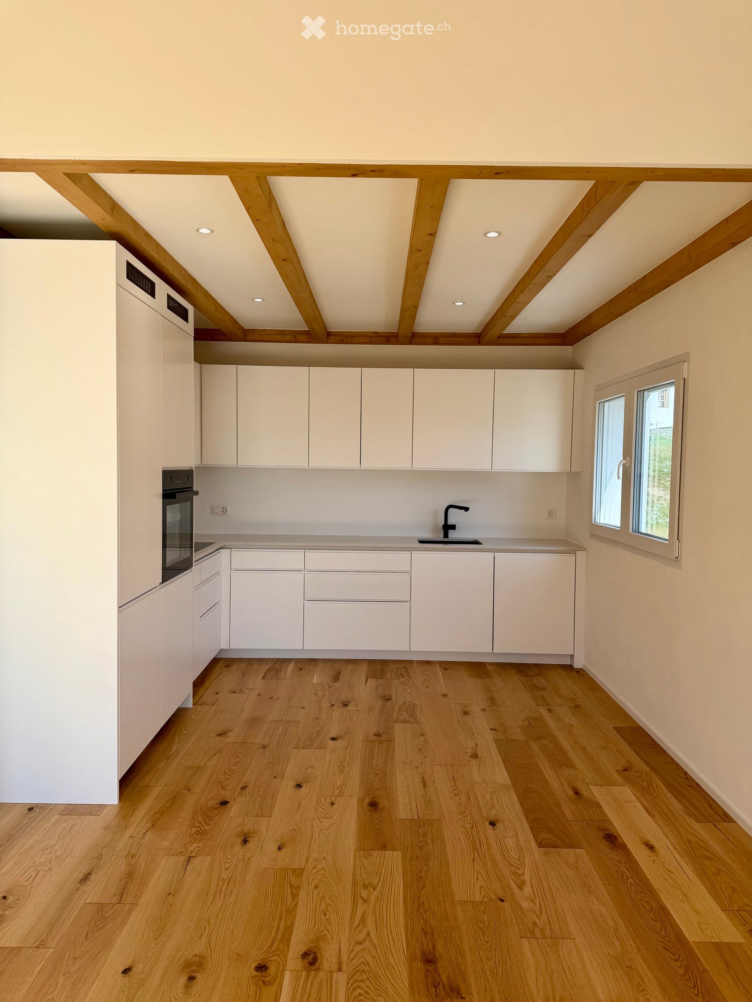 modern kitchen with white cabinets, wooden beams, wooden floor, sink, oven, window
