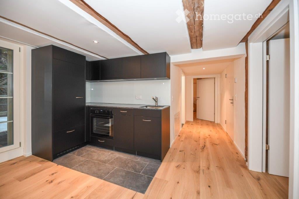 modern kitchen with black cabinets, wooden floor, white walls, oven, sink, faucet, glass door