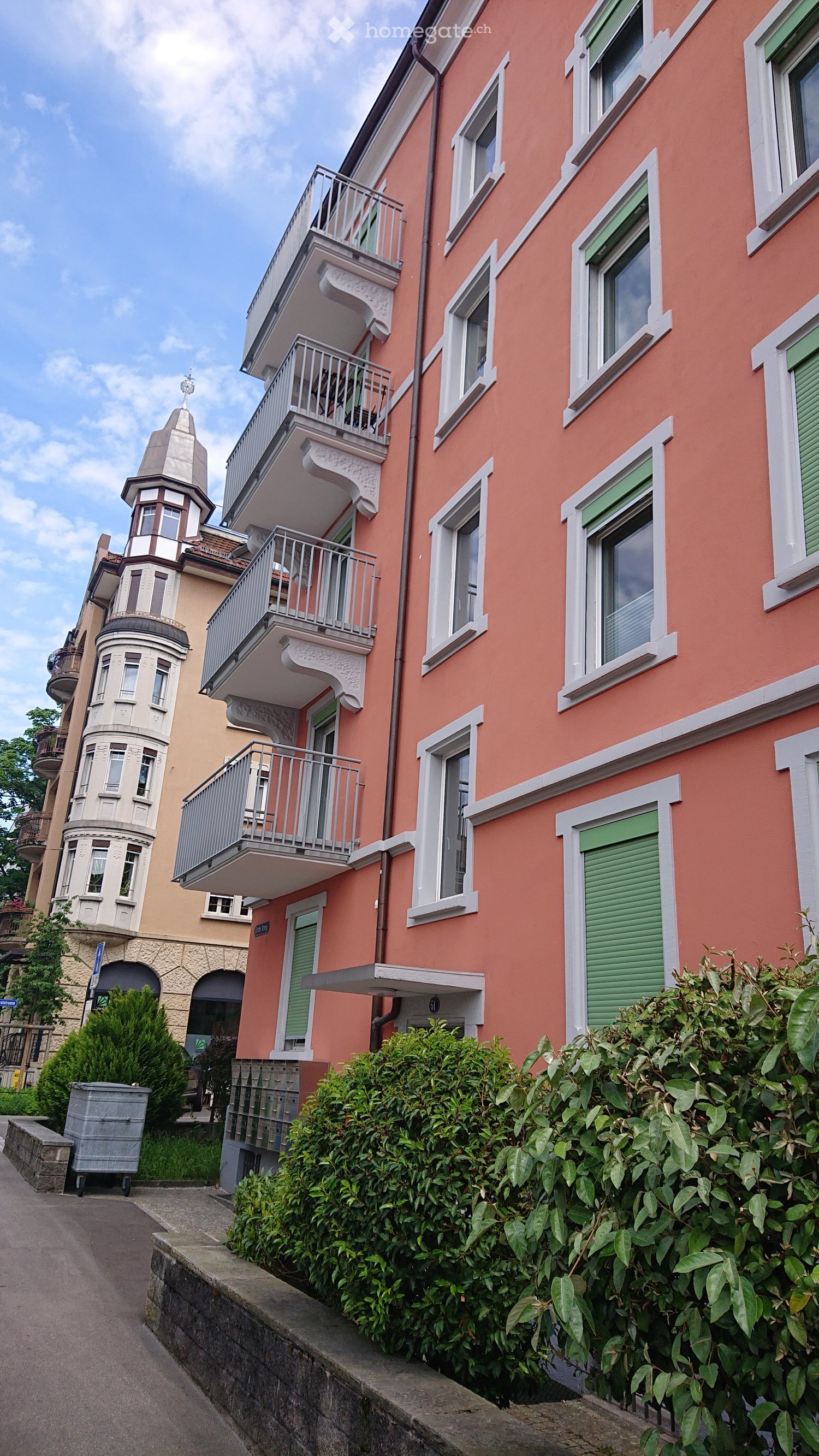 3 story building, pink exterior, white windows, green shutters, balconies