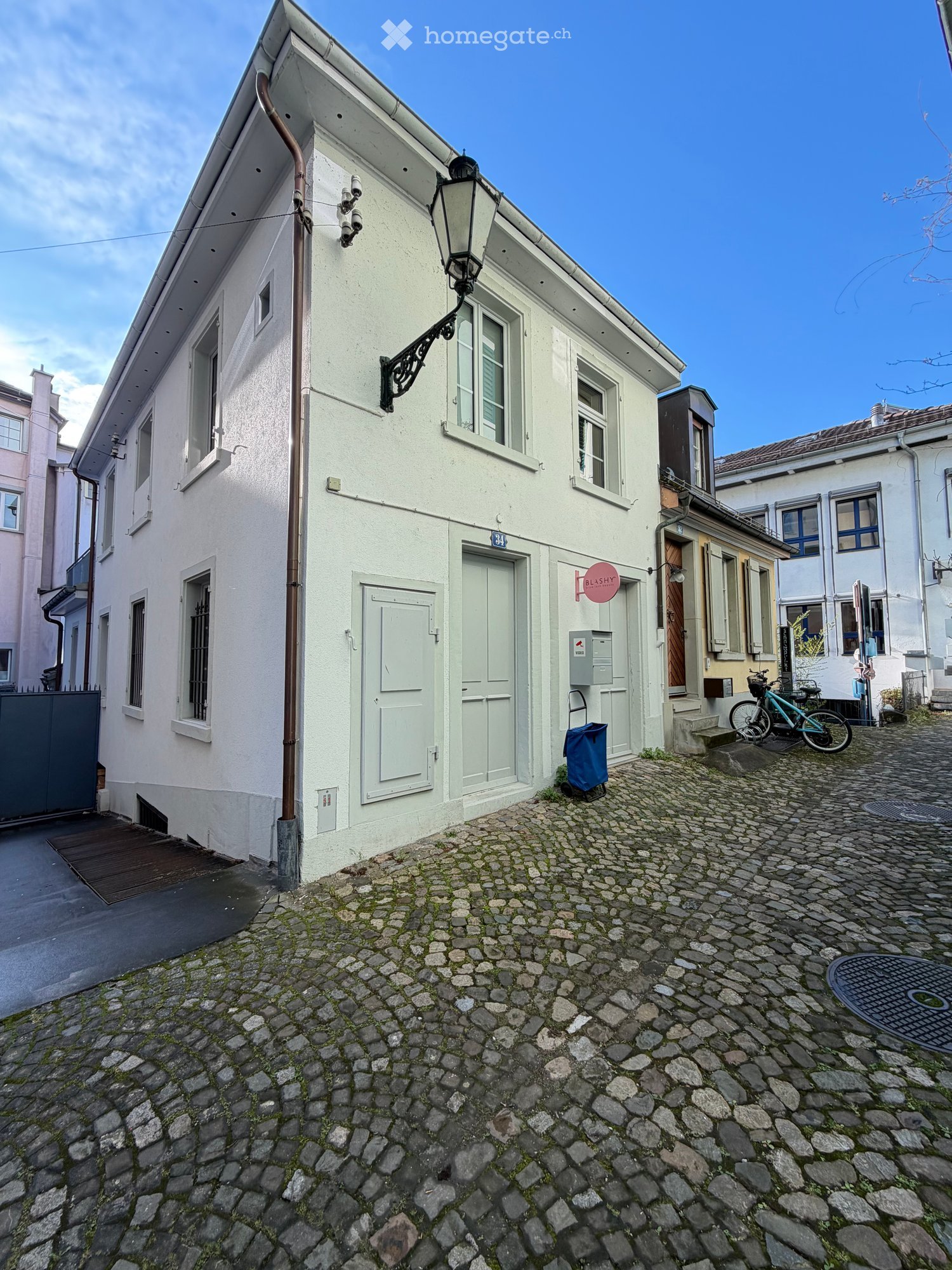 White house with multiple windows, two doors, bicycles parked in front, cobblestone street