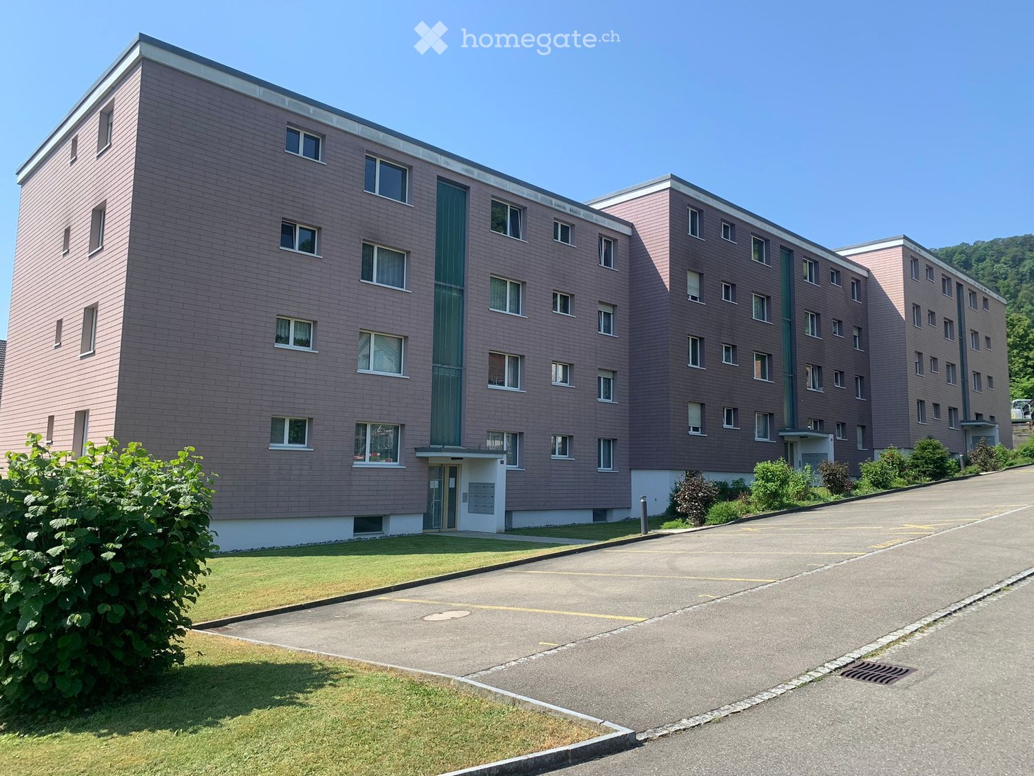 3 story apartment building, brick facade, multiple windows, parking lot in front