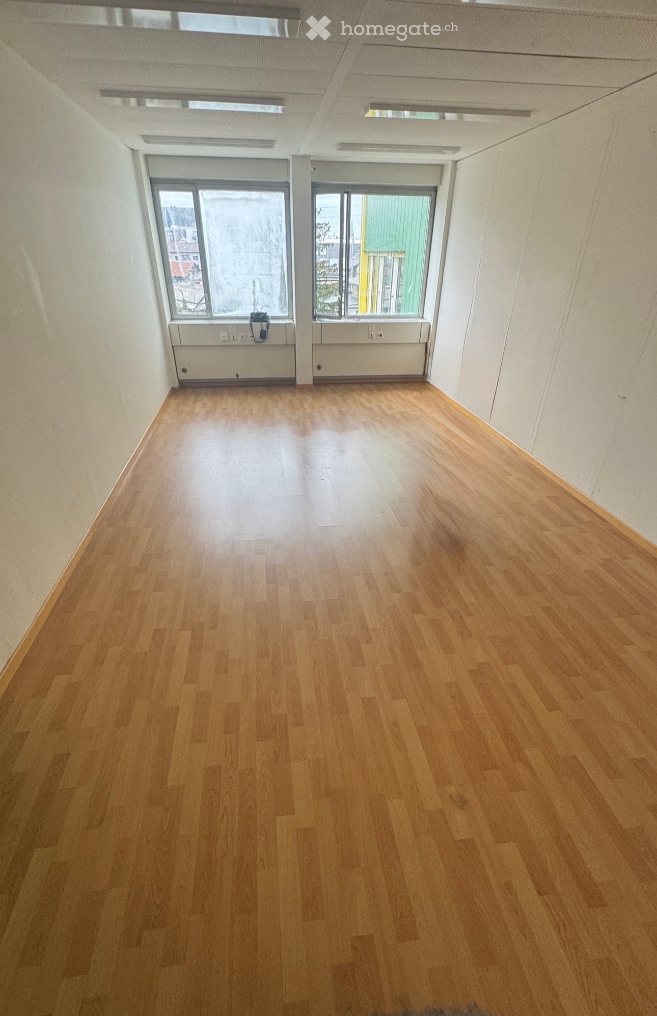 empty room, wooden floor, white walls, two windows, power outlets