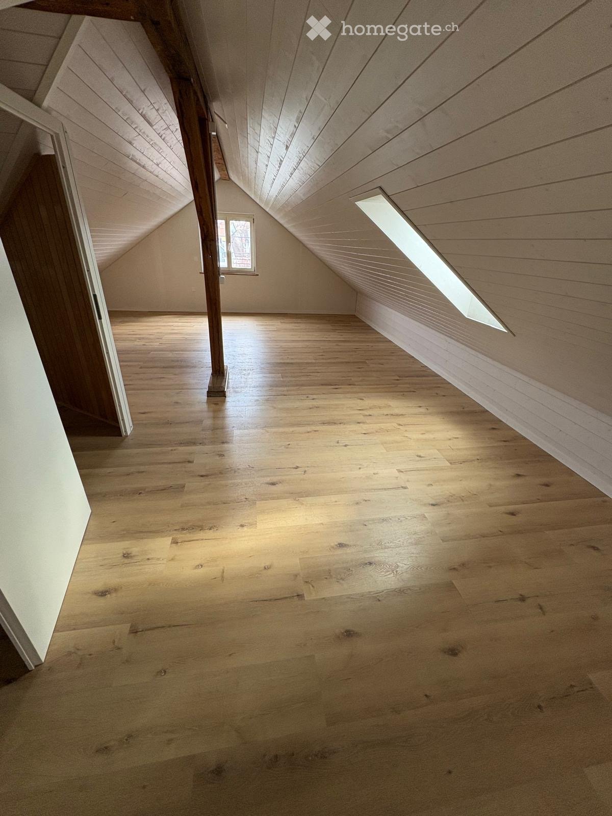 empty attic room, wooden floor, white walls, wooden beam, skylight