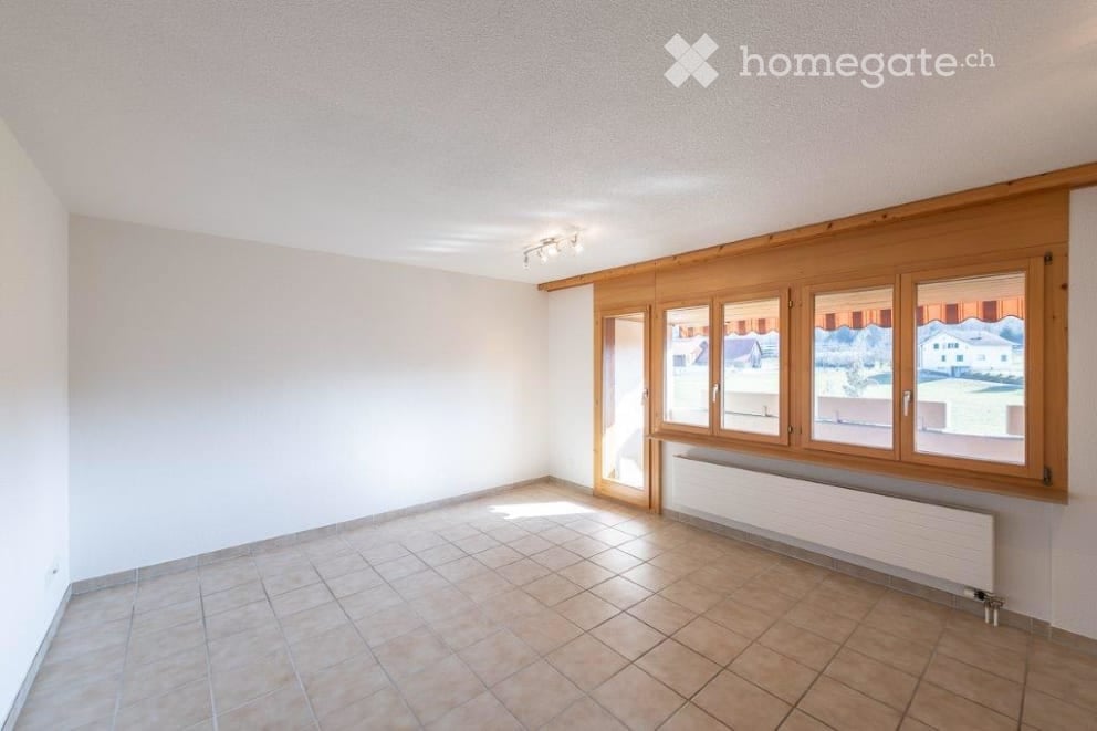 White walls, tiled floor, large windows with wooden frames, ceiling lights, white radiator