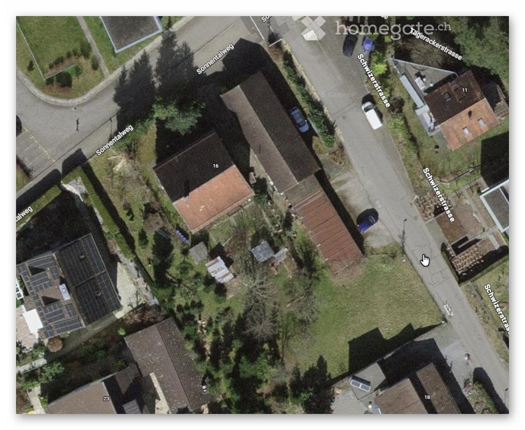 Aerial view of a residential area with several houses, driveways, and solar panels on some roofs.