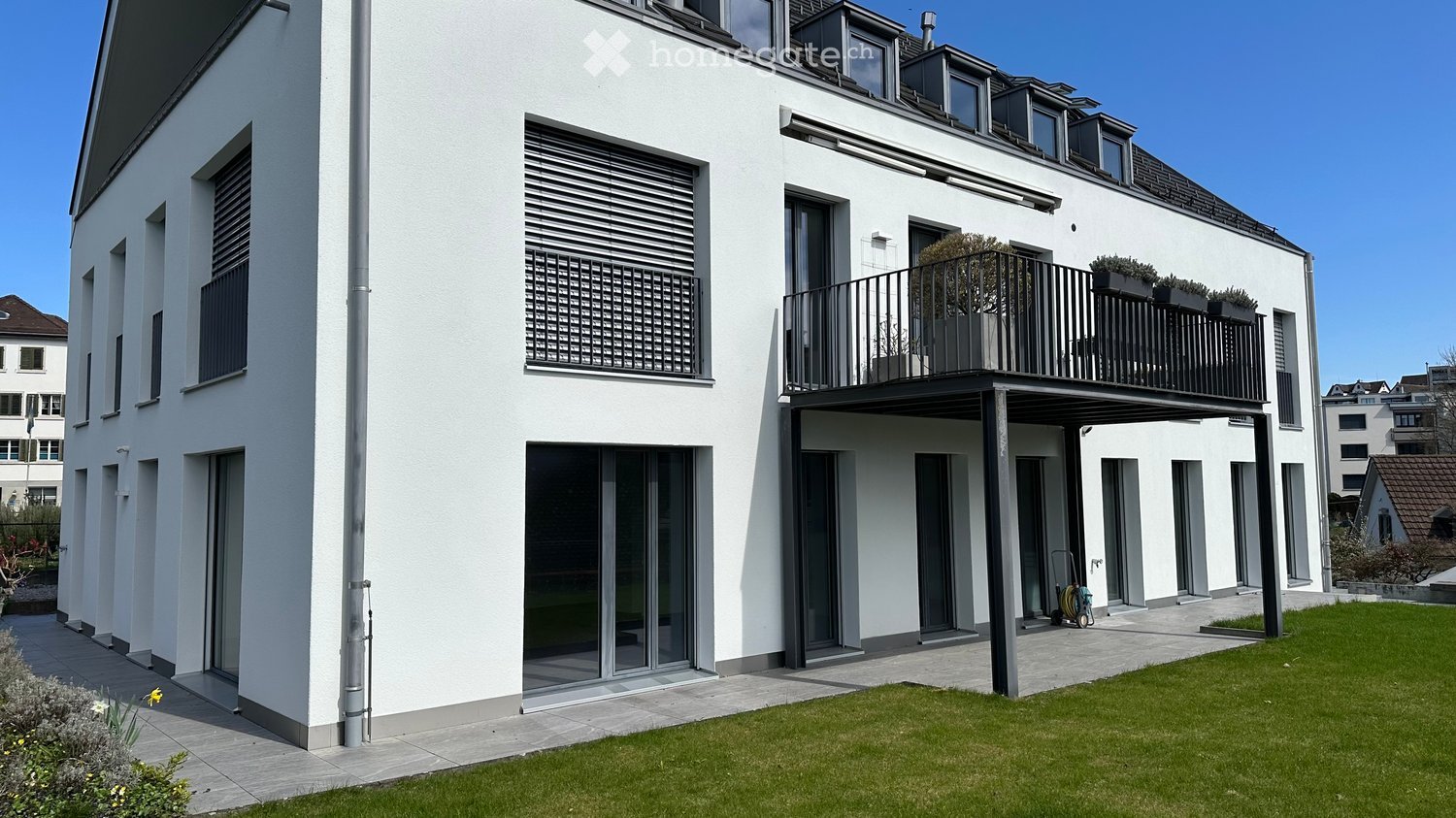 modern white house, 3 floors, balcony, glass doors, windows with shutters, green lawn