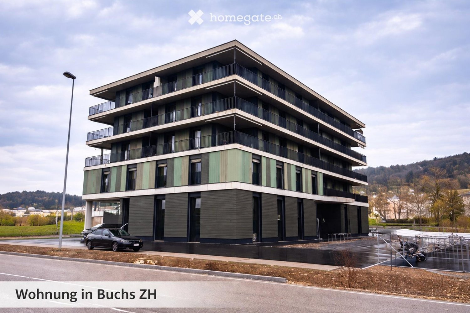 modern apartment building, multiple balconies, black and green exterior, car parked in front