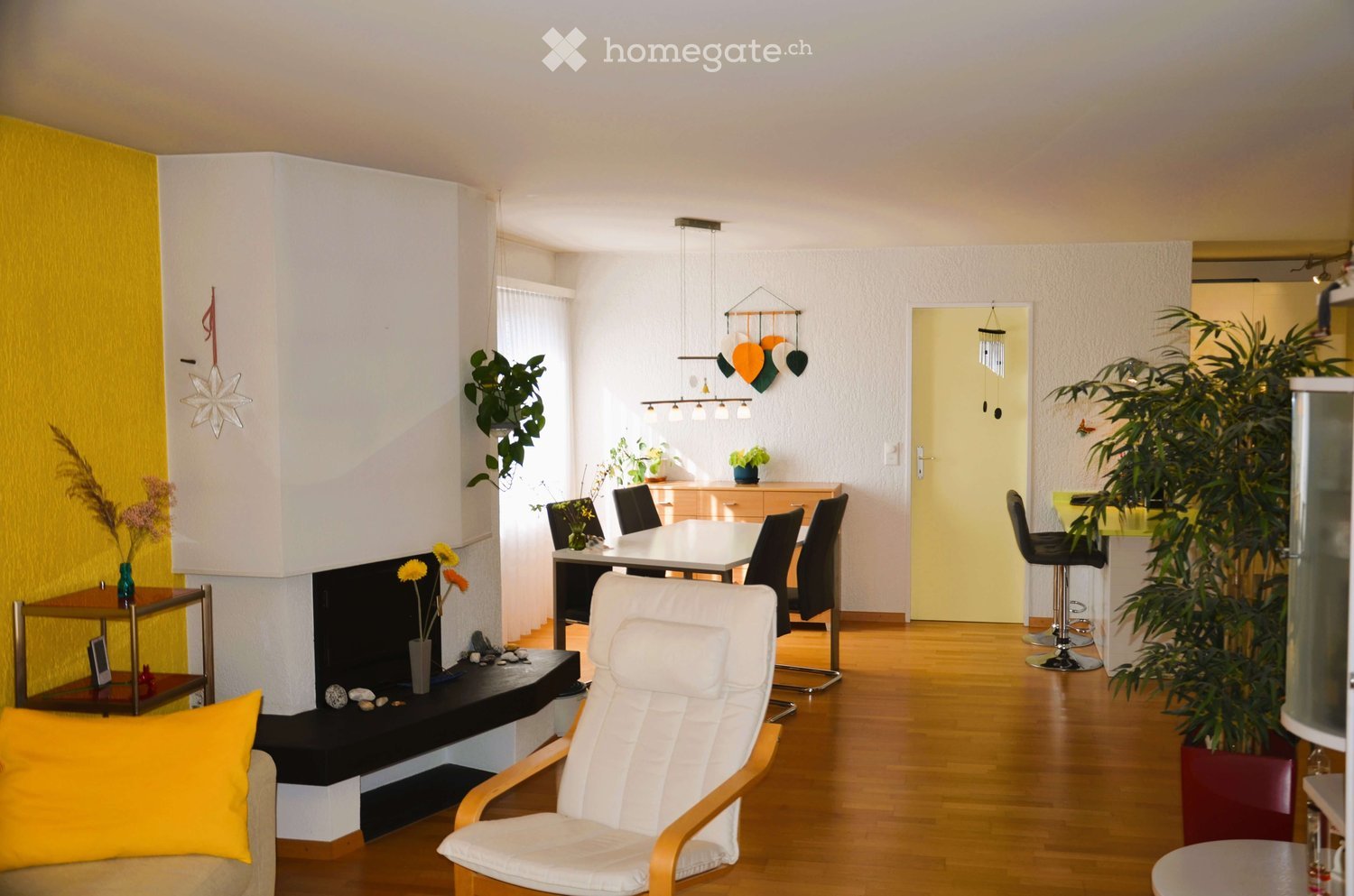 Fireplace, wooden floor, yellow walls, white furniture, plants, dining table, chairs, stools, decorative items