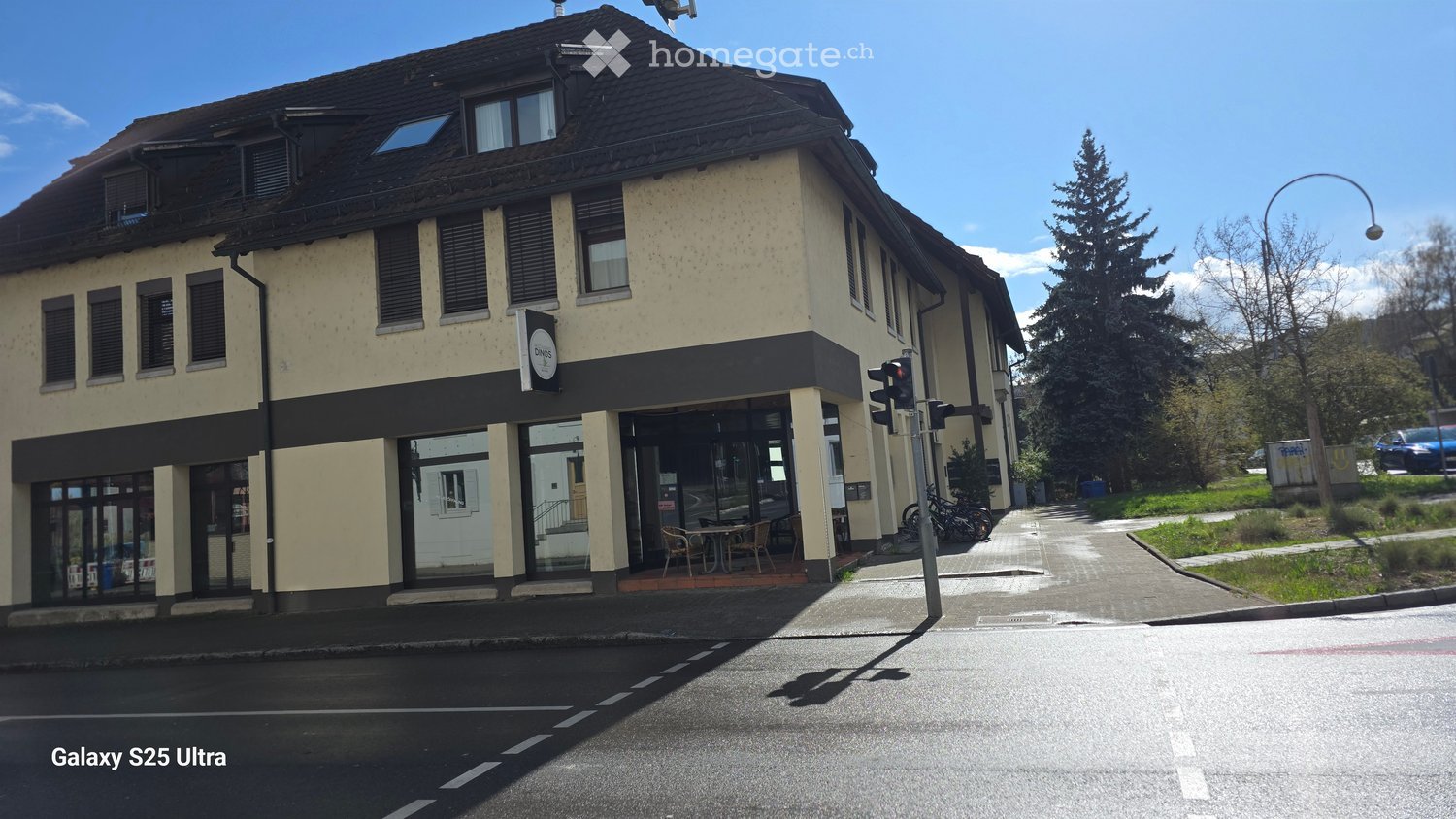 2 story building, beige walls, black roof, glass windows, outdoor seating, bicycles parked