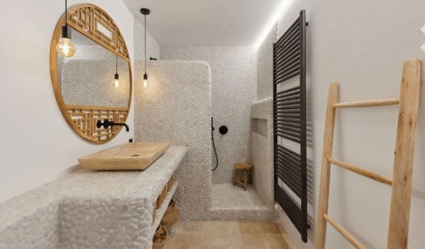 Bathroom with stone walls, wooden sink, round mirror, wooden stool, shower, wooden ladder