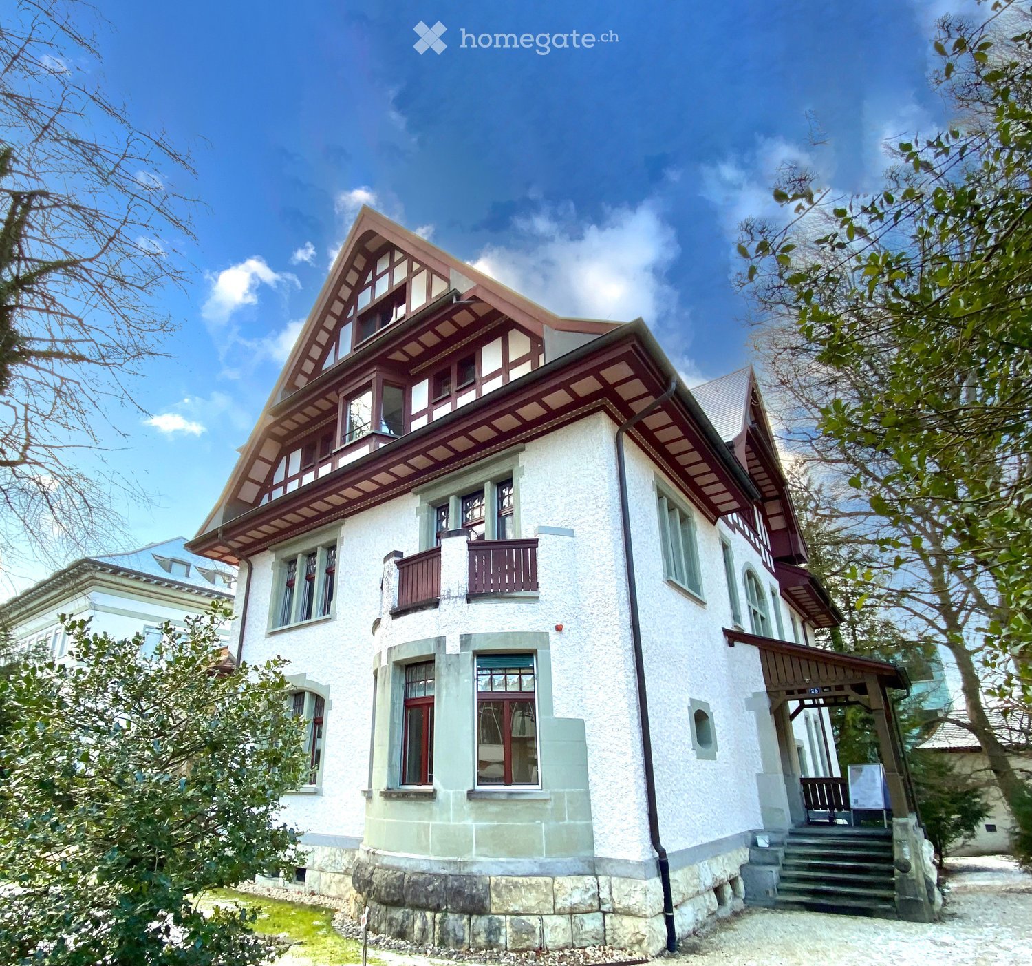 2 story house, white exterior, red trim, multiple windows, balcony, stone foundation
