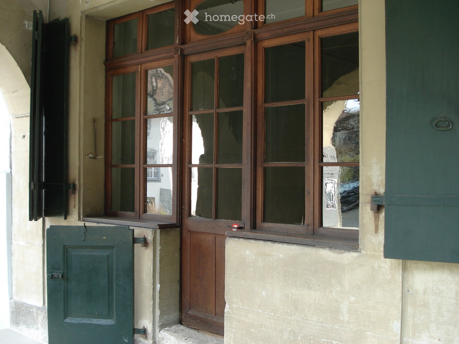 Facade with wooden door and windows, green shutters, beige wall