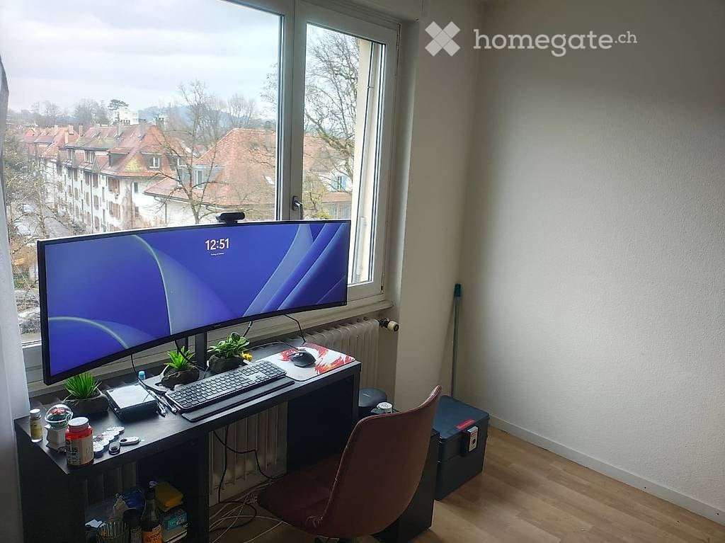 desk with computer, chair, plants, radiator, window with city view