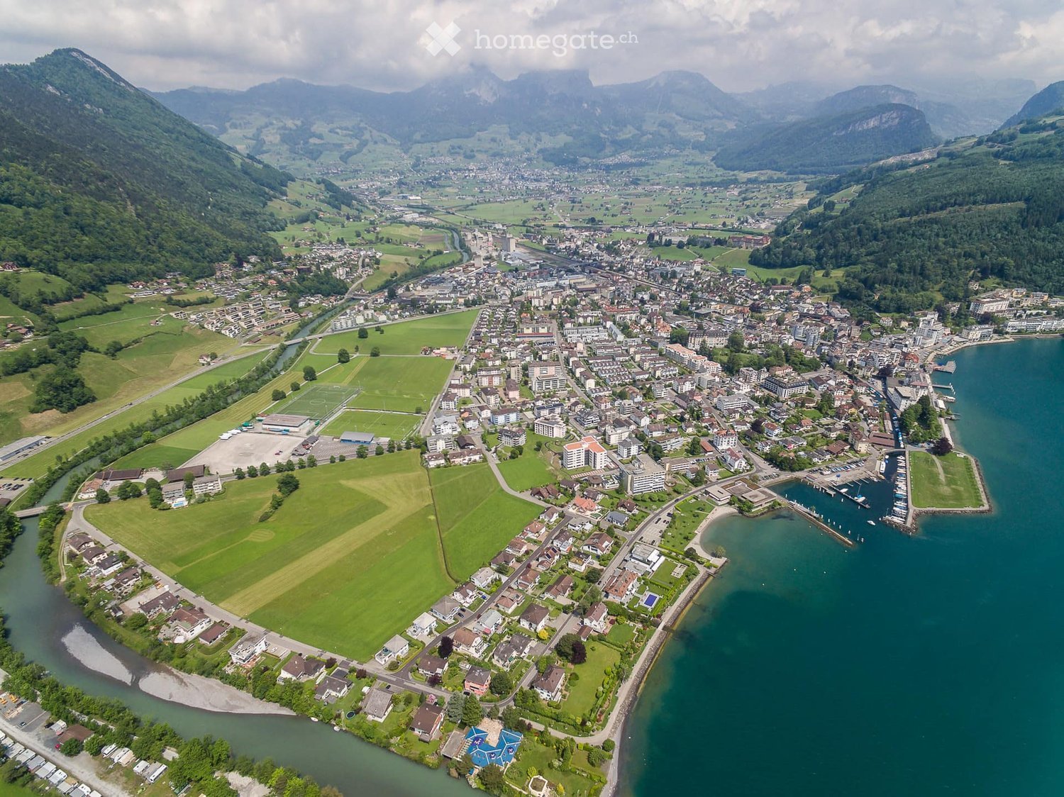 Aerial view of a town with many buildings, a river, and mountains in the background