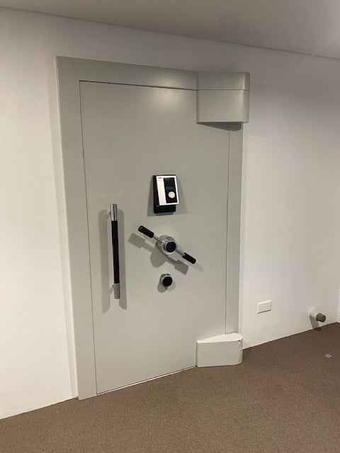 A room with a white door, a black handle, a black and silver lock, and a white wall