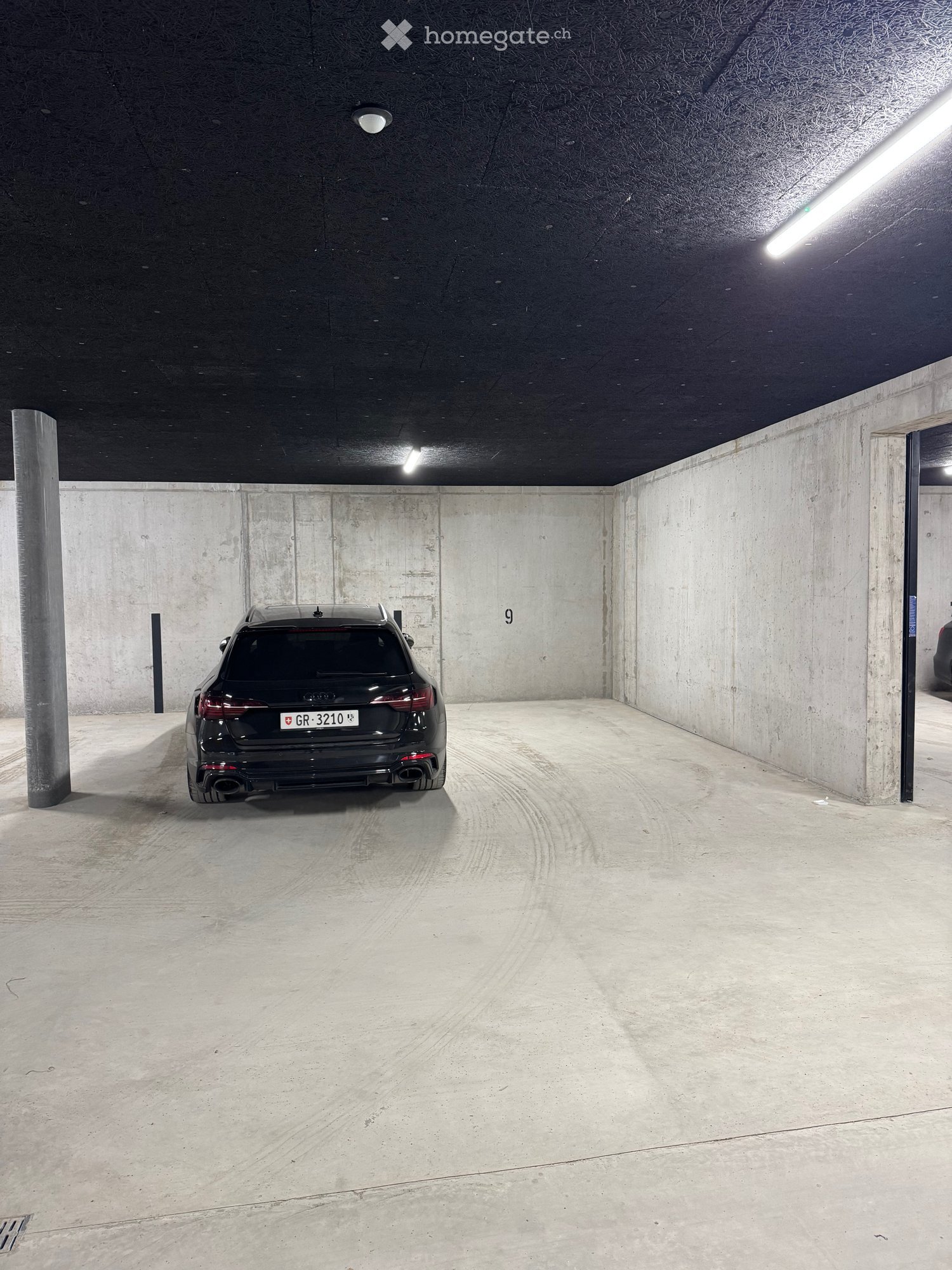 underground parking, concrete walls, ceiling lights, car parked