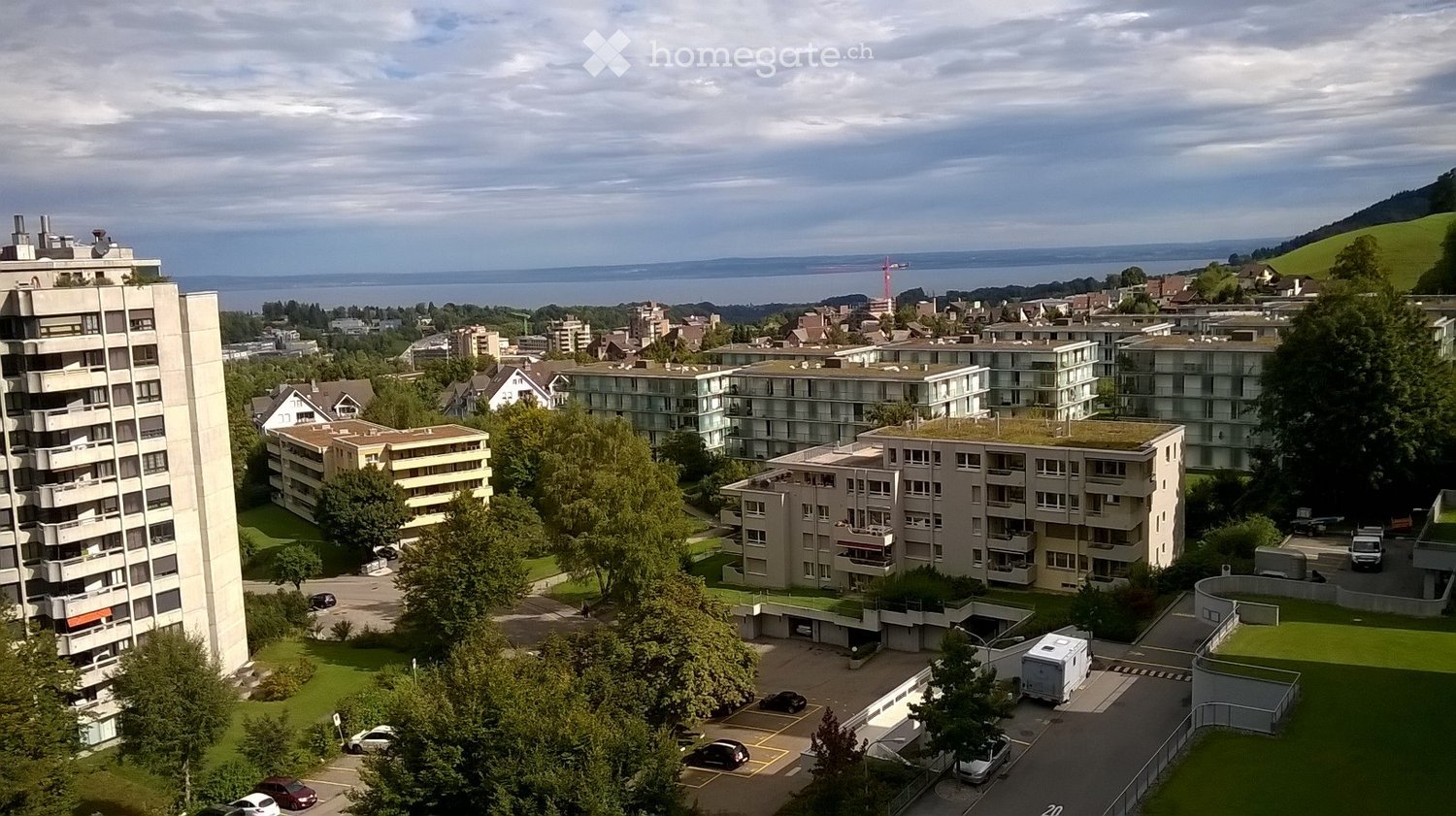 urban buildings, parking lots, green spaces, distant mountains, large body of water