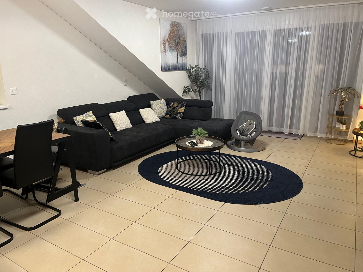 Living room with a black sofa, coffee table, rug, and a dining table with chairs.