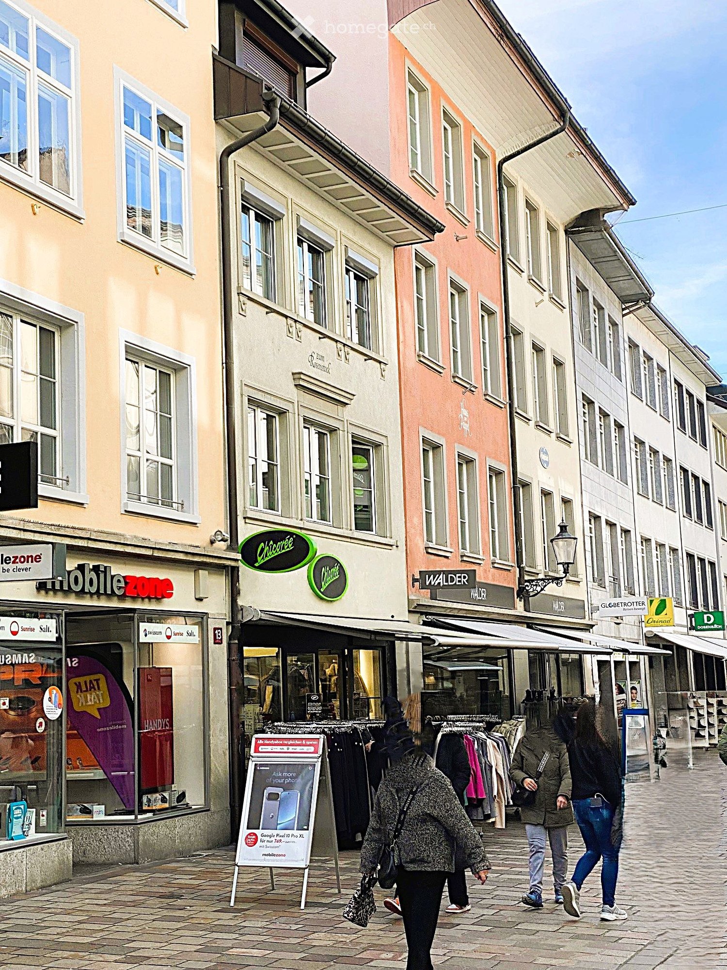 4 story building, modern architecture, storefronts, hanging lights, people walking