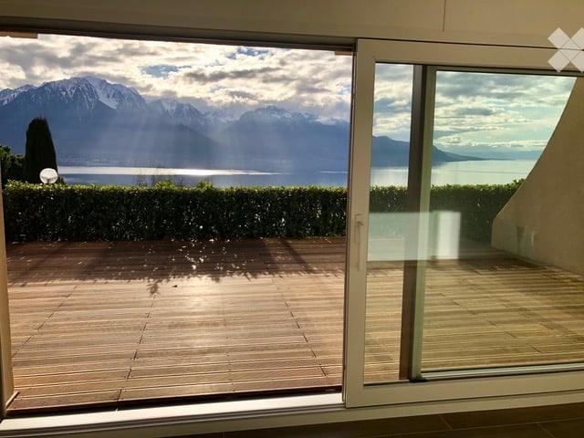 sliding glass door, wooden deck, hedges, lake, mountains