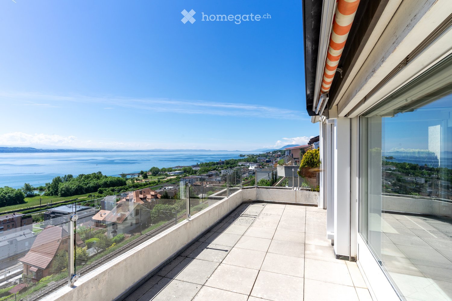 Balcony / Terrace. Balcony with tiled floor, glass railing, and expansive view of a lake and cityscape.