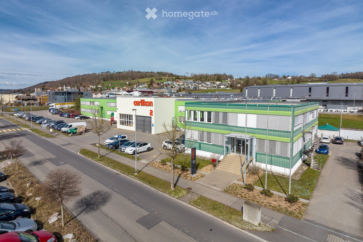 Industrial building, large parking lot, multiple cars parked, signage for Cerilikon.