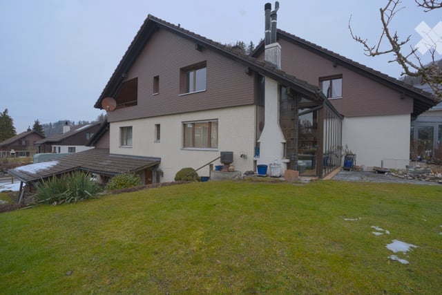 2 story house, brown and white exterior, glass windows, chimney, satellite dish, garden, lawn
