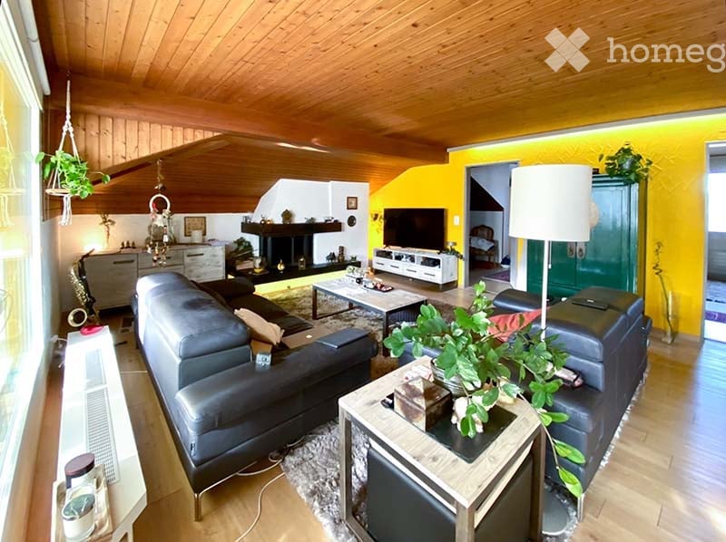 wooden ceiling, yellow wall, fireplace, black leather couches, coffee table, TV, lamp, potted plants