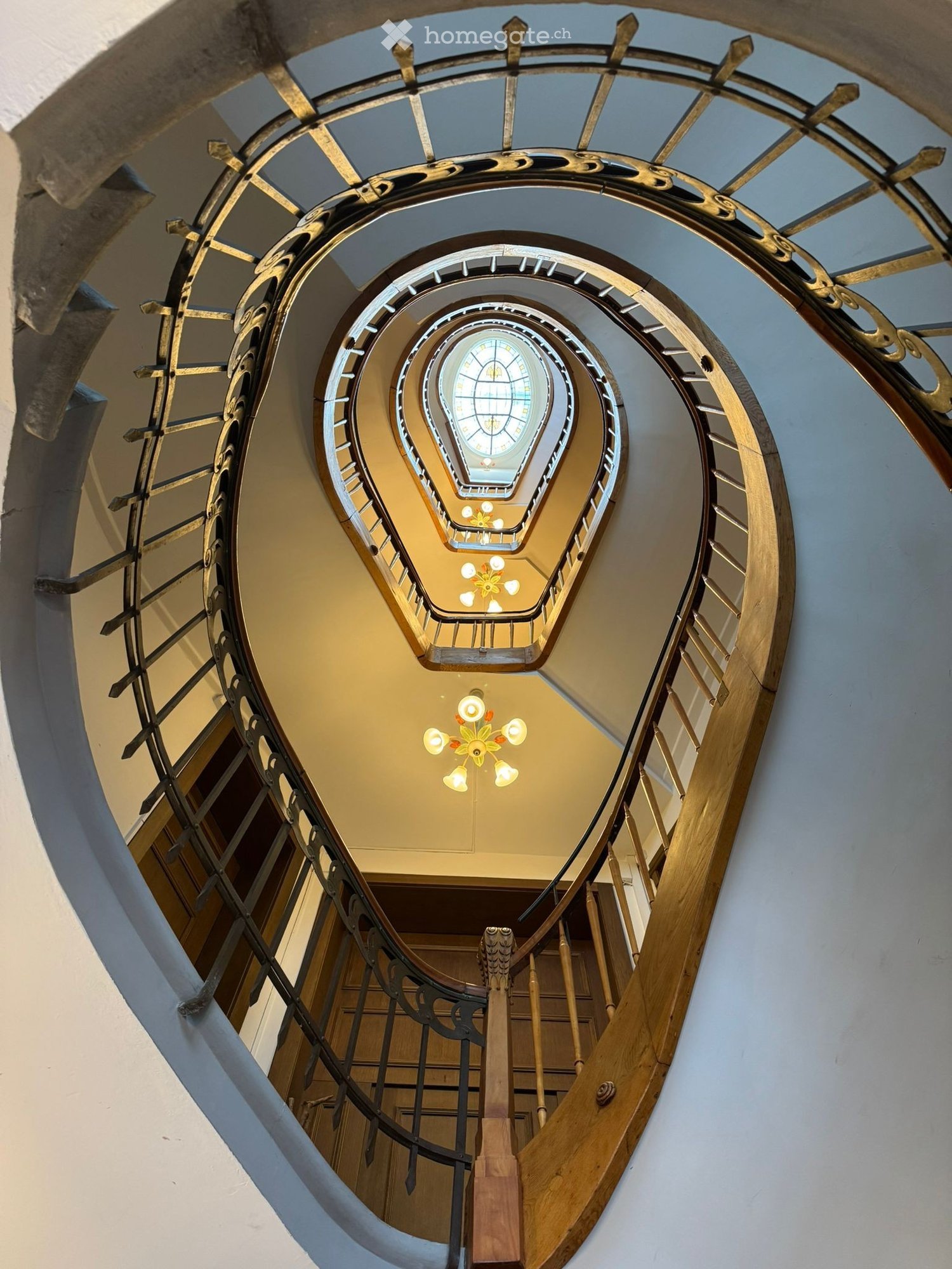 spiral staircase, wooden handrail, metal railing, stained glass window, chandelier