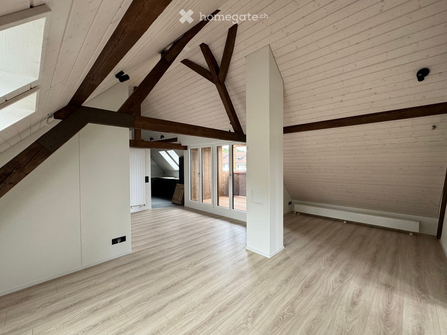empty attic room with wooden beams, wooden floor, glass doors, skylights