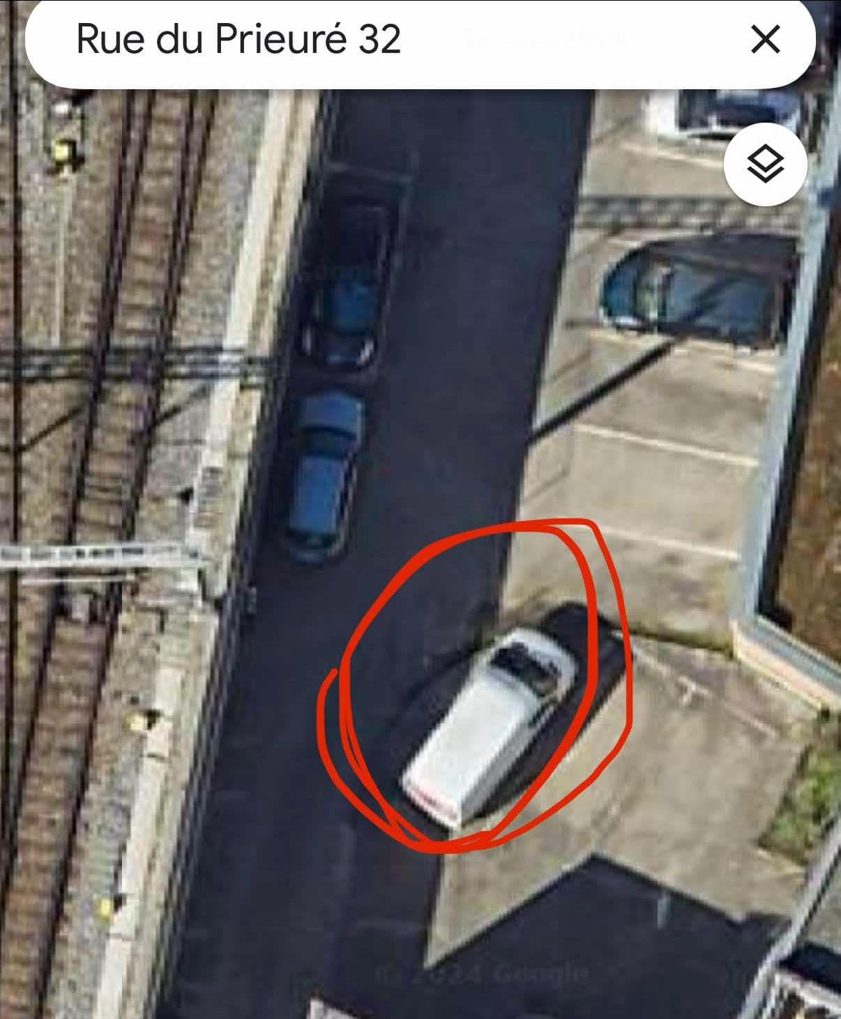 Aerial view of a parking lot with a car parked in a designated spot, surrounded by other cars and a building.