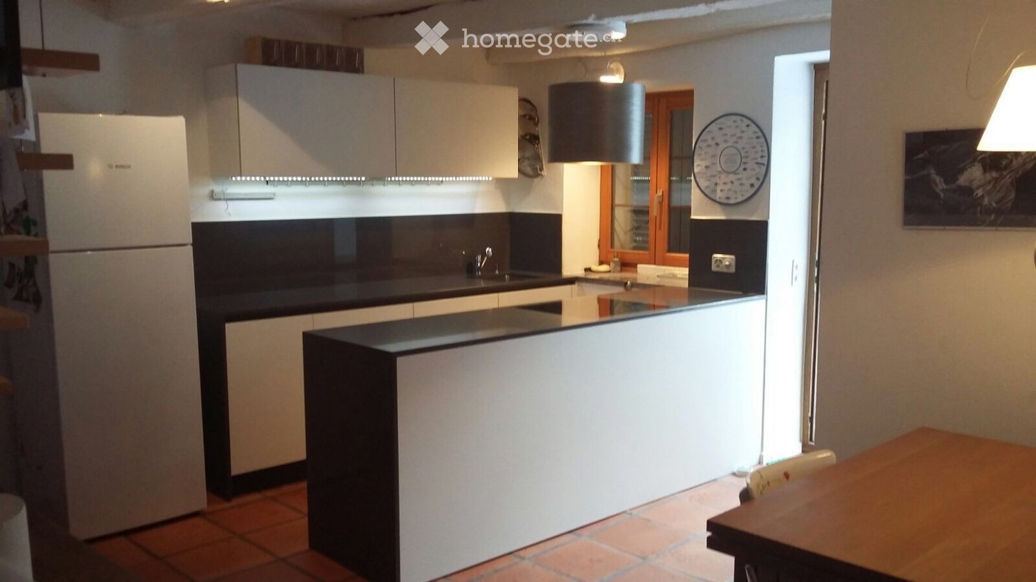 modern kitchen with white cabinets, black countertops, white refrigerator, sink, faucet, dishwasher, wooden table, lamps
