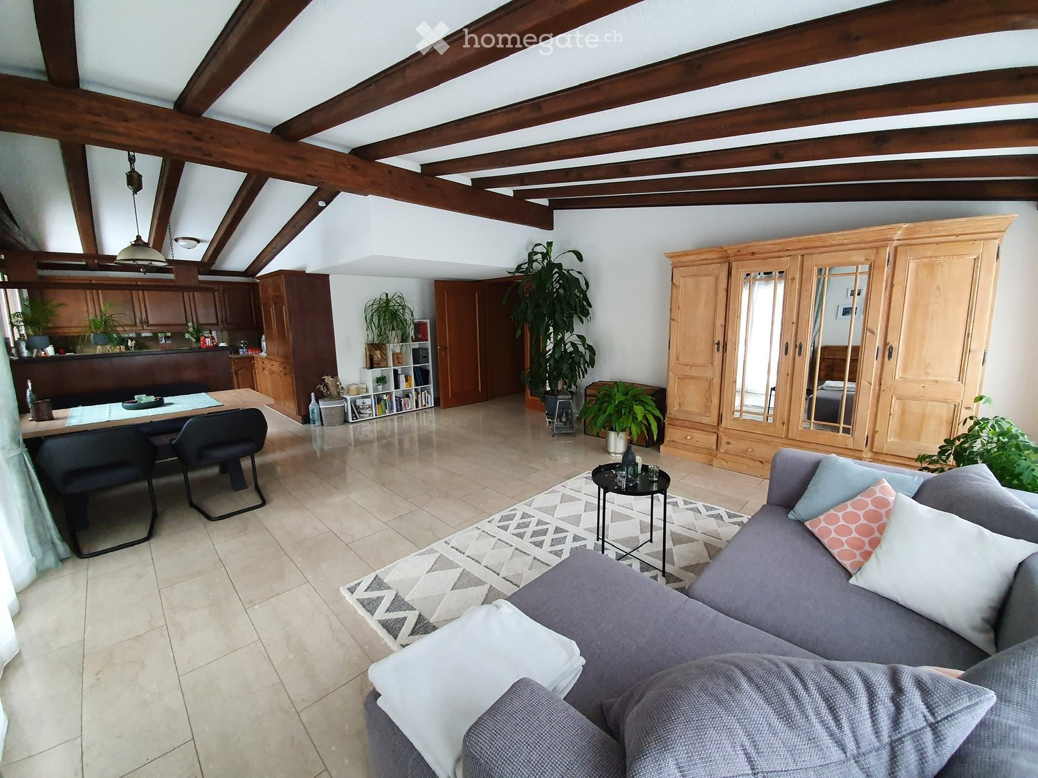 living room with wooden beams, white walls, beige tiles, wooden cabinet, couch, coffee table, rug, dining table, chairs, plants