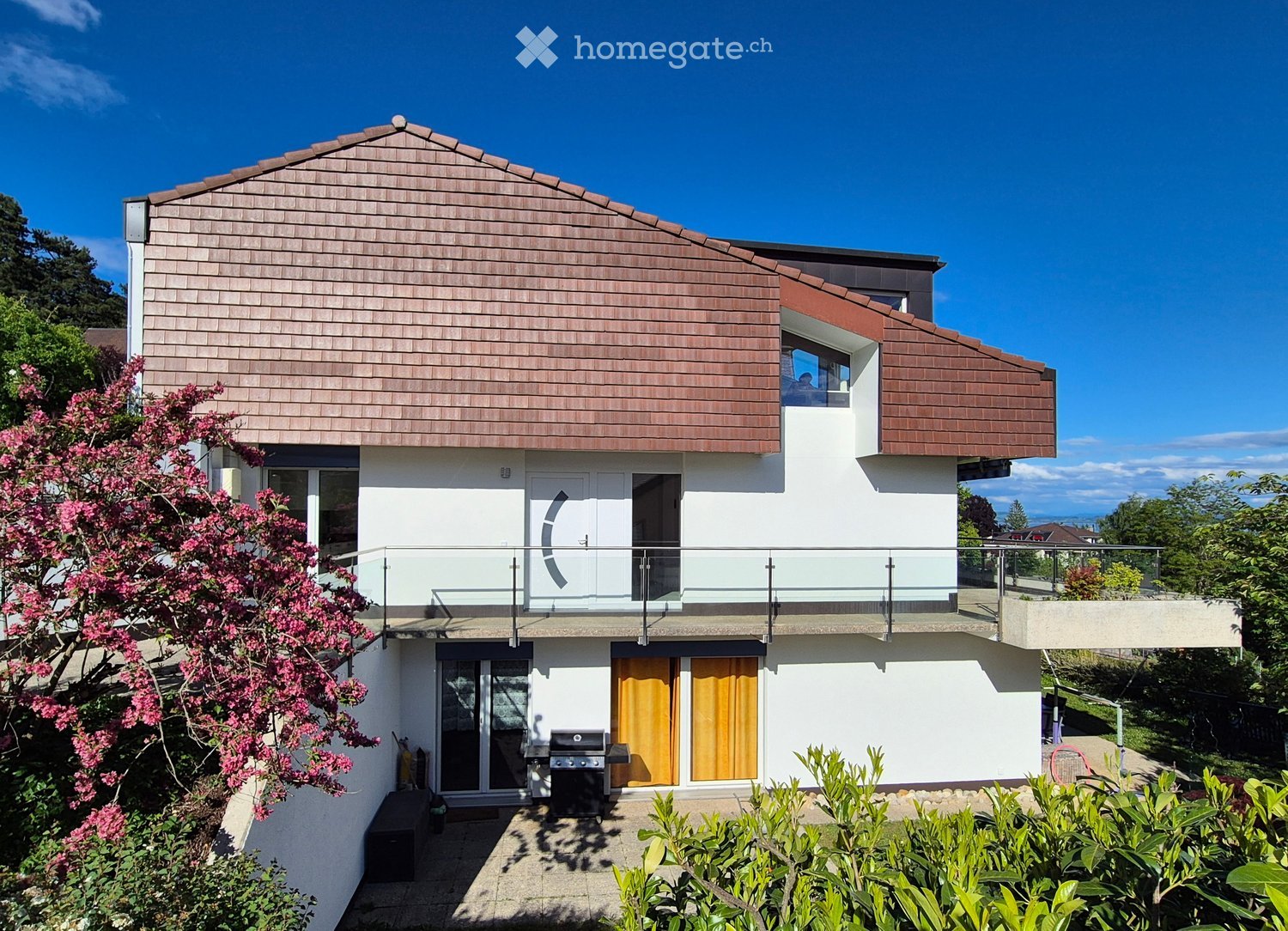 House. Modern two-story house with a sloped wooden roof, white walls, large windows, and a balcony. Features include a glass-enclosed balcony, orange shutters, and a barbecue in the front yard.